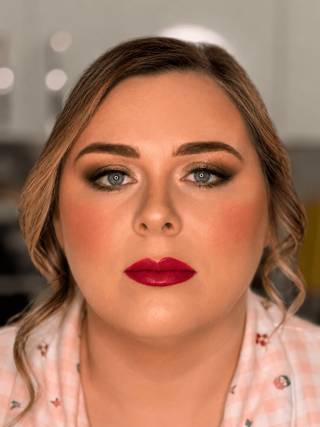 Fair-skinned woman with charcoal-brown smoky eye, sculpted brows, and classic bold red lip, party makeup by MZ Makeup Bedfordshire
